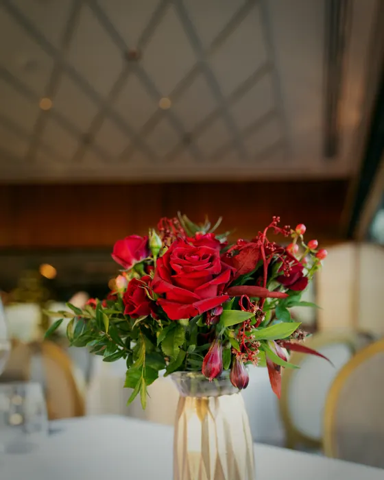 Rote Rosen in einer goldenen Vase auf dem gedeckten Tisch