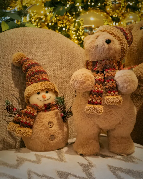 Teddybären und ein Schneemann vor den goldenen Bäumen